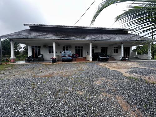 a house with two cars parked in front of it at Homestay Taman Hidayah Chawas in Tanah Merah
