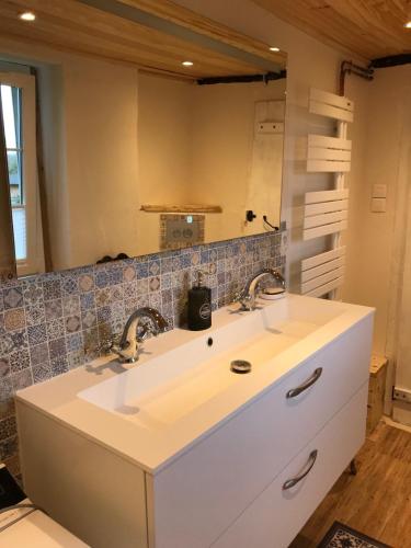 une salle de bain avec deux lavabos et un miroir dans l'établissement La Chaumière Enchantée, à Saint-Christophe-sur-Condé