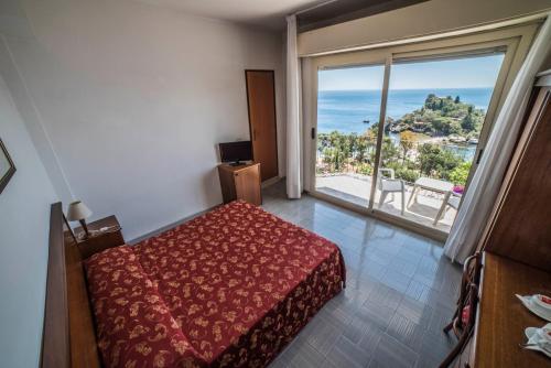 a bedroom with a bed and a large window at Hotel Isola Bella in Taormina