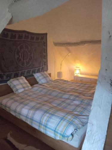 - une chambre dotée d'un lit avec une couverture tressée et une lampe dans l'établissement La Chaumière Enchantée, à Saint-Christophe-sur-Condé