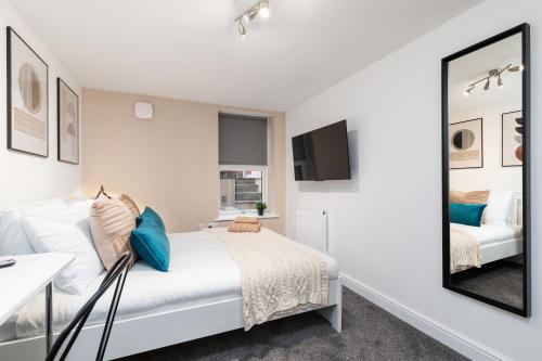 a white bedroom with a bed and a mirror at Luxury Lower-Level One Bed Apt in Headingley