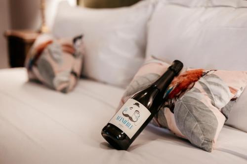 a bottle of wine sitting on top of a bed at Residenza San Vito in Calamandrana