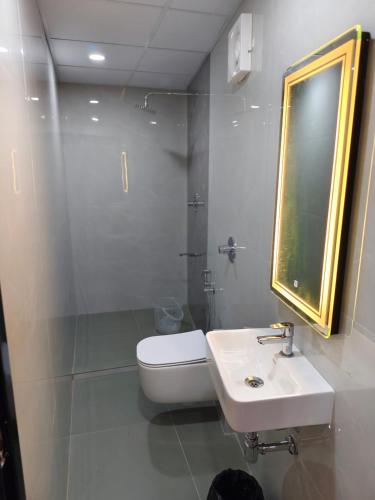 a bathroom with a sink and a toilet and a mirror at SG Mahal & Rooms in Kanyakumari