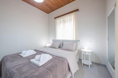 a white bedroom with a large bed with two white pillows at In the center of Messolonghi in Mesolongion