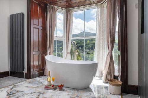 a bath tub in a bathroom with a large window at Eryri Snowdonia Premier Family Retreat with Hot Tub and Fire Pit in Dolgellau