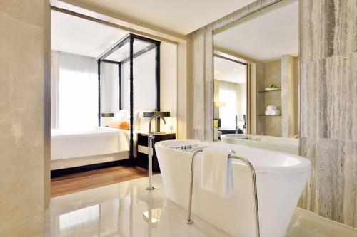 a bathroom with a white tub and a bedroom at Courtyard by Marriott Pune Hinjewadi in Pune