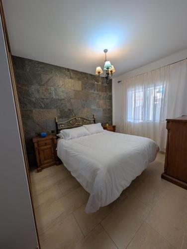 ein Schlafzimmer mit einem weißen Bett und einer Steinwand in der Unterkunft Villa romeritas in Puerto de Mazarrón