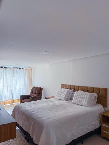 a bedroom with a large bed and two chairs at 230m da PRAIA, casa com ESPAÇO GOURMET e CHURRASQUEIRA, Portaria 24h, 2 VAGAS de GARAGEM, acomoda até 10 PESSOAS, Próximo a MERCADOS e FARMÁCIA in Salvador