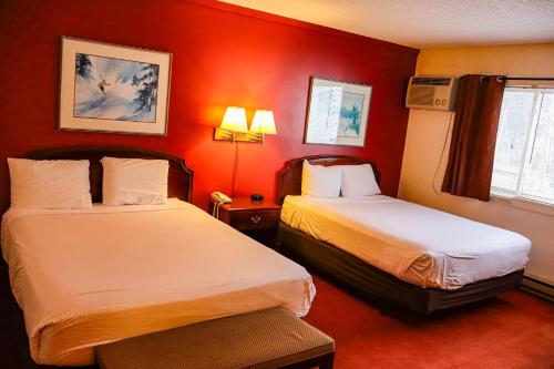 two beds in a hotel room with red walls at Snowy Owl Inn in Waterville Valley