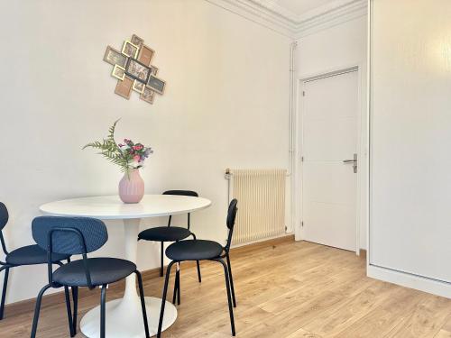 une table blanche avec des chaises et un vase de fleurs dans l'établissement Elegant Apt Sleep 5 in Alasseur Near Eiffel Tower, à Paris