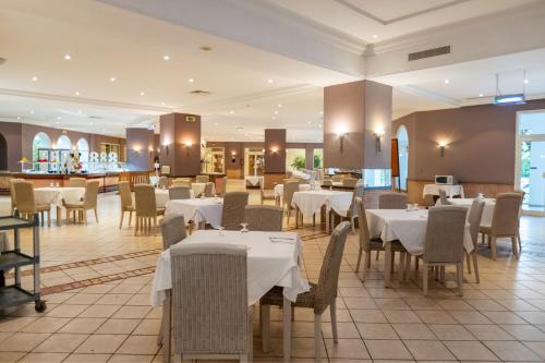a restaurant with white tables and chairs and a bar at Djerba Resort- Families and Couples Only in Houmt Souk