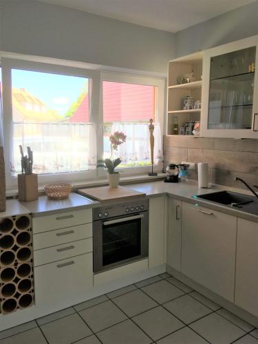 a kitchen with white appliances and two windows at FeWo Honighof Hümmling in Neu Heinde