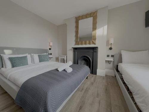 a white bedroom with two beds and a fireplace at Number One Hundred Bed And Breakfast in Cardiff