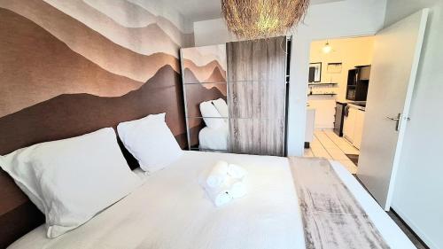 une chambre avec un lit avec des oreillers blancs dans l'établissement Appartement cosy, balcon et place privée, au Mans
