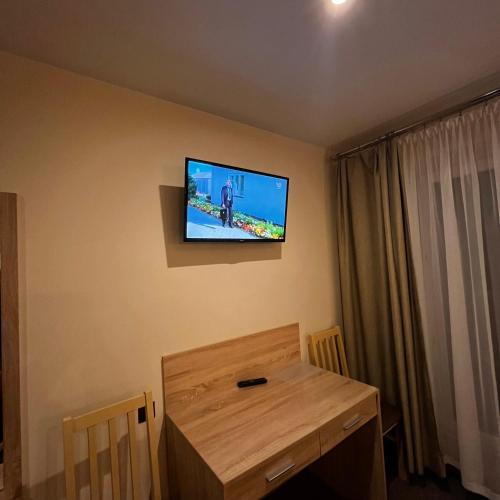 a room with a television on the wall with a wooden table at Valda House in Rybie