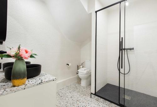 La salle de bains est pourvue de toilettes et d'un vase de fleurs sur un comptoir. dans l'établissement Cosy Apartment - Parc des expositions Tour Eiffel 2, à Paris