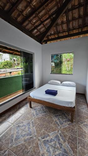 a bed in a room with two large windows at LahSelva Pousada e Hostel in Itacaré