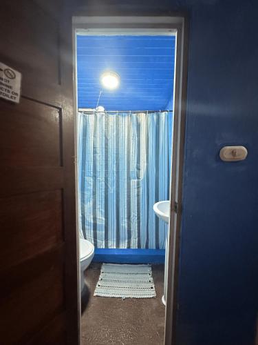 a bathroom with a toilet and a window with a light at Chosa Manglar Suites & Cabins in Puerto Jiménez