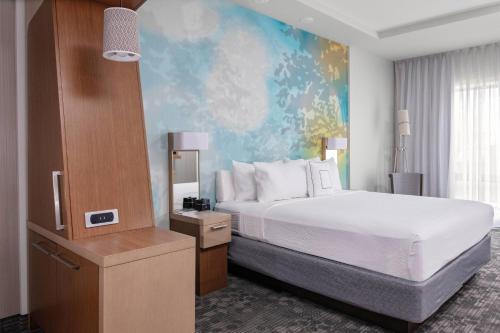 a hotel room with a bed and a painting on the wall at Courtyard by Marriott East Lansing Okemos in Okemos