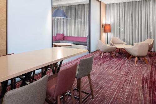 a room with a table and chairs and a couch at Courtyard by Marriott East Lansing Okemos in Okemos