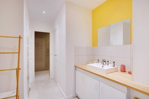 une salle de bain blanche avec un lavabo et un miroir dans l'établissement Loft moderne et chic 130 m2- Ménilmontant, à Paris