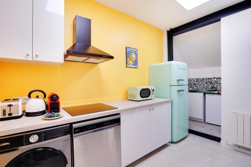 Il comprend une cuisine équipée d'un réfrigérateur et d'une cuisinière. dans l'établissement Loft moderne et chic 130 m2- Ménilmontant, à Paris