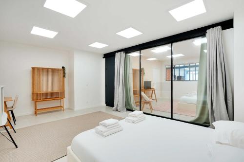une chambre avec un lit blanc et une grande fenêtre dans l'établissement Loft moderne et chic 130 m2- Ménilmontant, à Paris