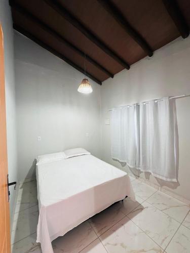 a white bedroom with a white bed and curtains at Vila Limeira in Porto Seguro