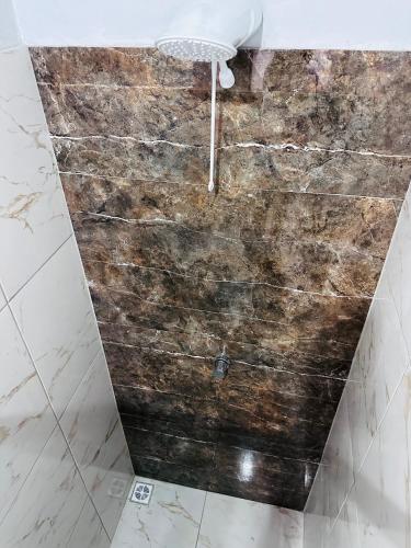 a shower in a bathroom with a wooden wall at Vila Limeira in Porto Seguro