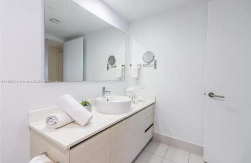 Un baño blanco con lavabo y espejo. en 2 Bed 2 Bath at Beachwalk with Luxury Pool and Gym, en Hallandale Beach