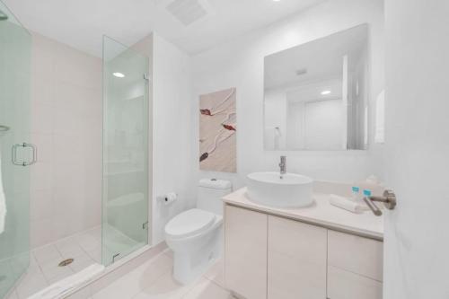 baño blanco con aseo y ducha acristalada en Luxury 2BR-2BA Condo on 30th Floor with Epic Views, en Hallandale Beach