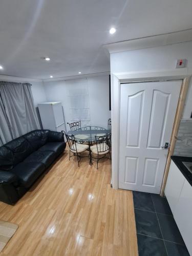 a living room with a black leather couch and a glass table at Garden house in Tilbury