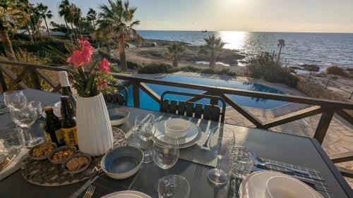 a table with food and wine on a balcony with the ocean at Villa Galatea Stunning First Line Beachfront in Khlorakas