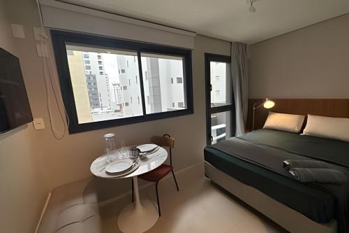 a bedroom with a bed and a table with a window at Ap Luxury Jardins Masp Cd 405 in Sao Paulo