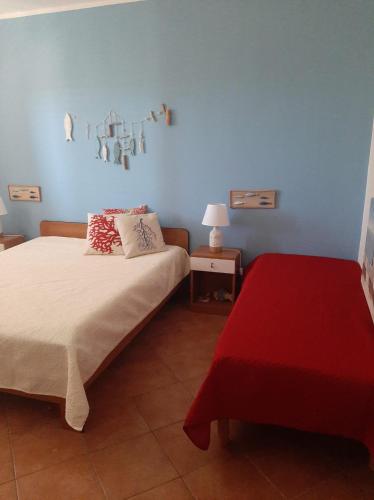 a bedroom with two beds and a blue wall at Residence Le Perle Beach in San Vito lo Capo