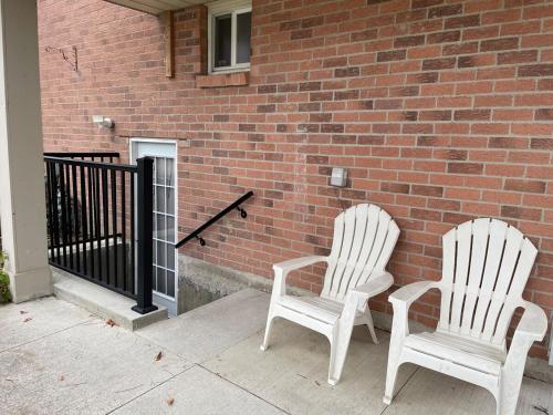 two white chairs sitting next to a brick wall at CozyHaven A private entrance, comfy basement apartment in Mississauga with free parking Conveniently located with easy access to the airport downtown Toronto major malls and highways for a seamless stay in Mississauga