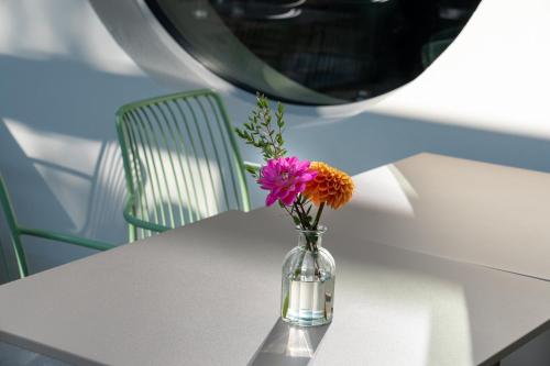 a vase filled with flowers sitting on a table at Aparthotel Il Momento Bern Expo - Self Check-In Hotel in Bern