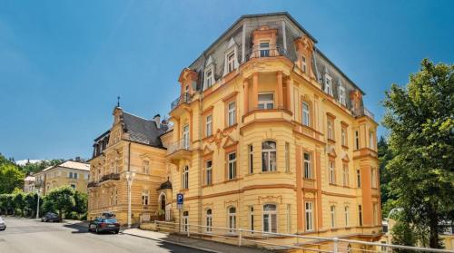 a large yellow building in front of a street at Anzio apartments in Mariánské Lázně