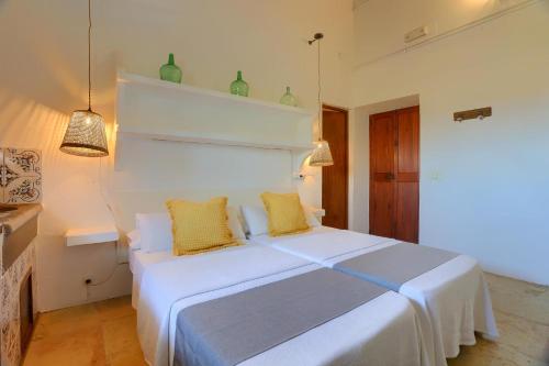 a bedroom with a white bed with two yellow pillows at Agroturismo Finca Son Valls - Adults Only in Felanitx