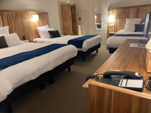a hotel room with three beds and a desk with a phone at Logis Hôtel de France & Restaurant Pamiers in Pamiers