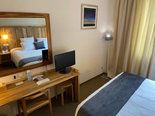 a hotel room with a desk with a bed and a mirror at Logis Hôtel de France & Restaurant Pamiers in Pamiers
