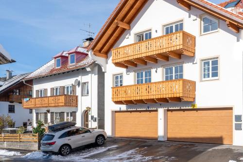 a car parked in front of a building with wooden balconies at LIBORIA I Traumhafte Ferienwohnung in Aidling am Riegsee in Riegsee
