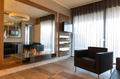 a living room with a fireplace and a black chair at Villaverde Hotel Spa&Golf Udine in Fagagna
