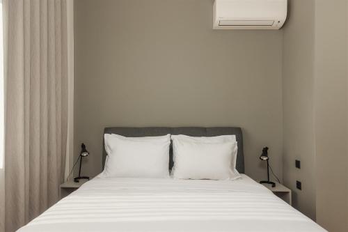 a bed with white sheets and two pillows at Anvy Stylish Suites Ioannina in Ioannina