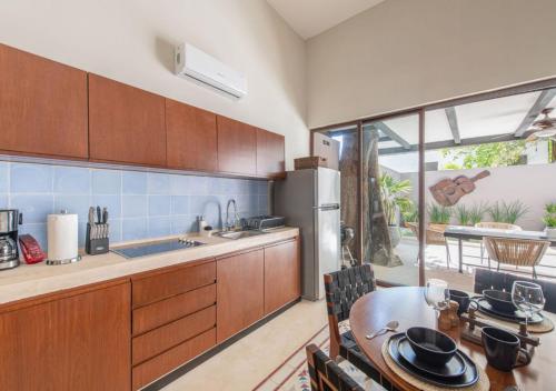 a kitchen with wooden cabinets and a table with a dining room at Casa Balada Santa Lucía with Parking by Cercana in Mérida
