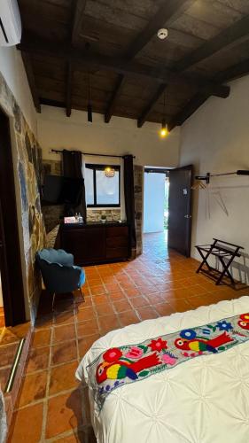 a bedroom with two beds and a room with a television at La Peña Hotel Boutique & SPA in Cuetzalán del Progreso