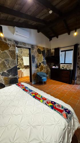 a large bed in a room with a stone wall at La Peña Hotel Boutique & SPA in Cuetzalán del Progreso