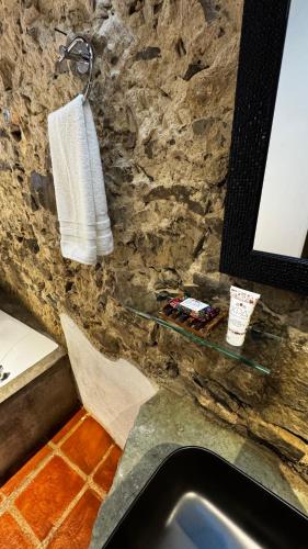 a bathroom with a sink and a towel on a stone wall at La Peña Hotel Boutique & SPA in Cuetzalán del Progreso