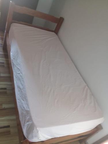 a small bed with white sheets on a wooden frame at Casa em Arembepe in Camaçari