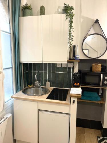 une cuisine avec des armoires blanches et un évier dans l'établissement Le Cosy, charmant studio centre ville, à Rennes
